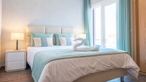 A hotel room with a large bed, a nightstand, a lamp, and a window with curtains. - Luxury Villa w/ Jacuzzi and Heatable Pool (Armação de Pêra)