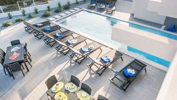 A rooftop pool area with lounge chairs, tables, and a dining setup.