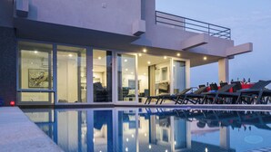 A modern hotel with a swimming pool, large windows, and a well-lit interior. - Luxury Villa w/ Jacuzzi and Heatable Pool (Armação de Pêra)