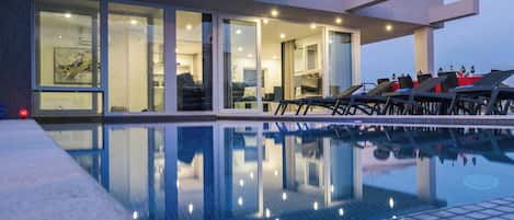 Um hotel moderno com piscina, grandes janelas e interior bem iluminado.