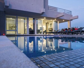 A modern hotel with a swimming pool, large windows, and a well-lit interior.