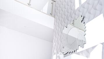 Un intérieur moderne aux couleurs claires, principalement blanches, agrémenté d’un décor mural original et d’un élément décoratif central rappelant un éventail ou une fleur.