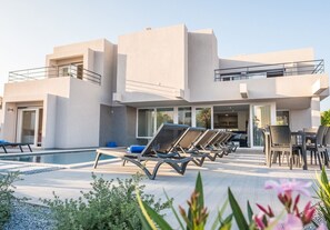 A modern building with a pool area, including lounge chairs and a dining table. - Luxury Villa w/ Jacuzzi and Heatable Pool (Armação de Pêra)