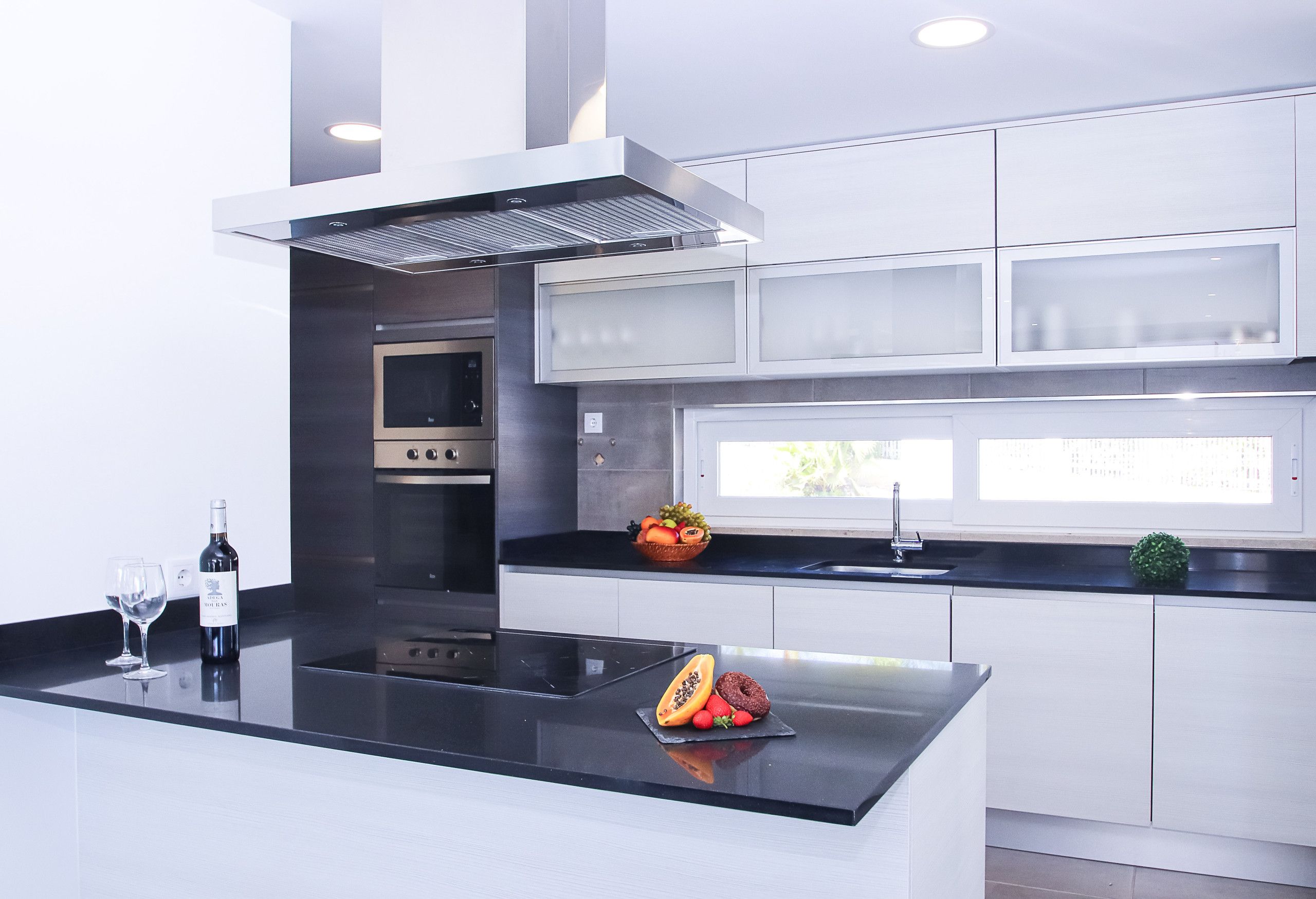 A modern kitchen with a central island, stainless steel appliances, and a window providing natural light.