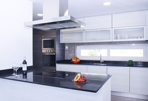 A modern kitchen with a central island, stainless steel appliances, and a window providing natural light. - Luxury Villa w/ Jacuzzi and Heatable Pool (Armação de Pêra)