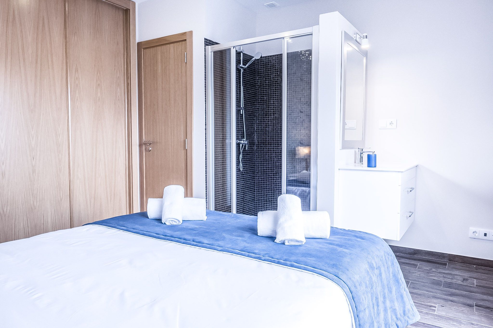 A hotel room with a bed, a shower area, and a white dresser.