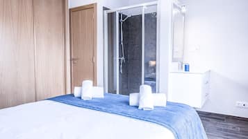 A hotel room with a bed, a shower area, and a white dresser.