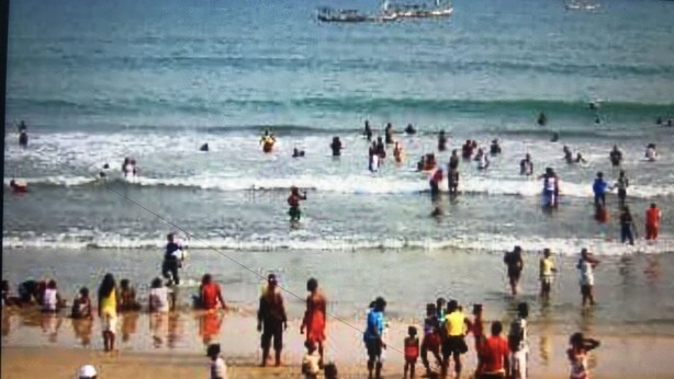 Une plage bondée où les gens pratiquent diverses activités.