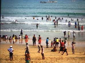 A crowded beach with people engaging in various activities.