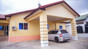 Un bâtiment à deux étages doté d’un abri-voiture et d’une voiture garée.