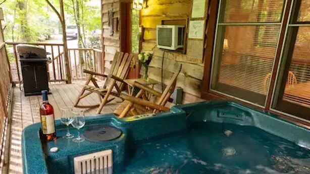 Ein Whirlpool mit einer Holzterrasse, einem Grill und einem Stuhl.