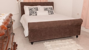Una cama con cabecera marrón, ropa de cama blanca y almohadas estampadas con diseño de cebra.