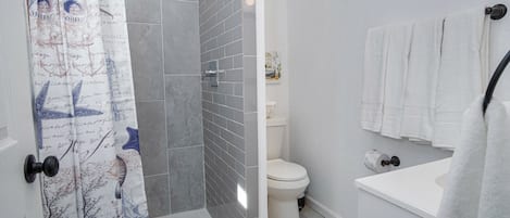 A bathroom with a shower, toilet, and sink.