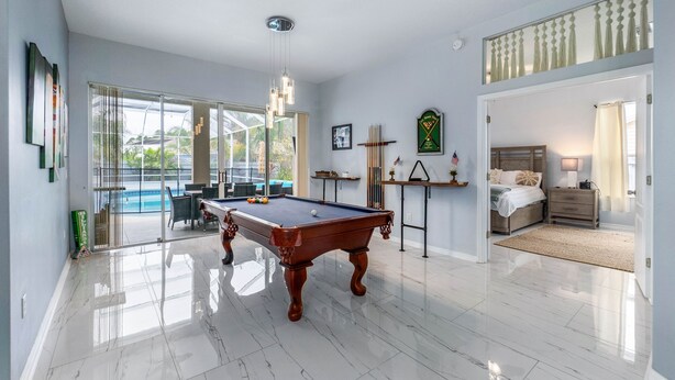 A spacious room with a pool table, a bed, and a view of the outdoors. - Palm Coast Oasis Retreat- 15 min to beach (Palm Coast)