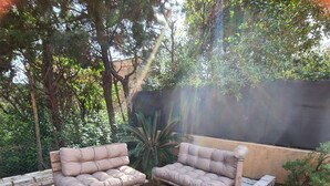Patio esterno con due divani imbottiti, un tavolino in legno e un muro in pietra.