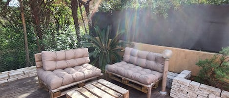 An outdoor patio with two cushioned sofas, a wooden coffee table, and a stone wall.