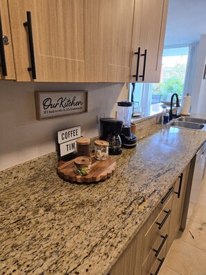 Eine Küche mit Holzausstattung, einer Arbeitsplatte aus Granit, einer Kaffeemaschine und einem Schild mit der Aufschrift 'Unsere Küche. Wenn ich sie umrühren müsste, ist sie selbstgemacht.'