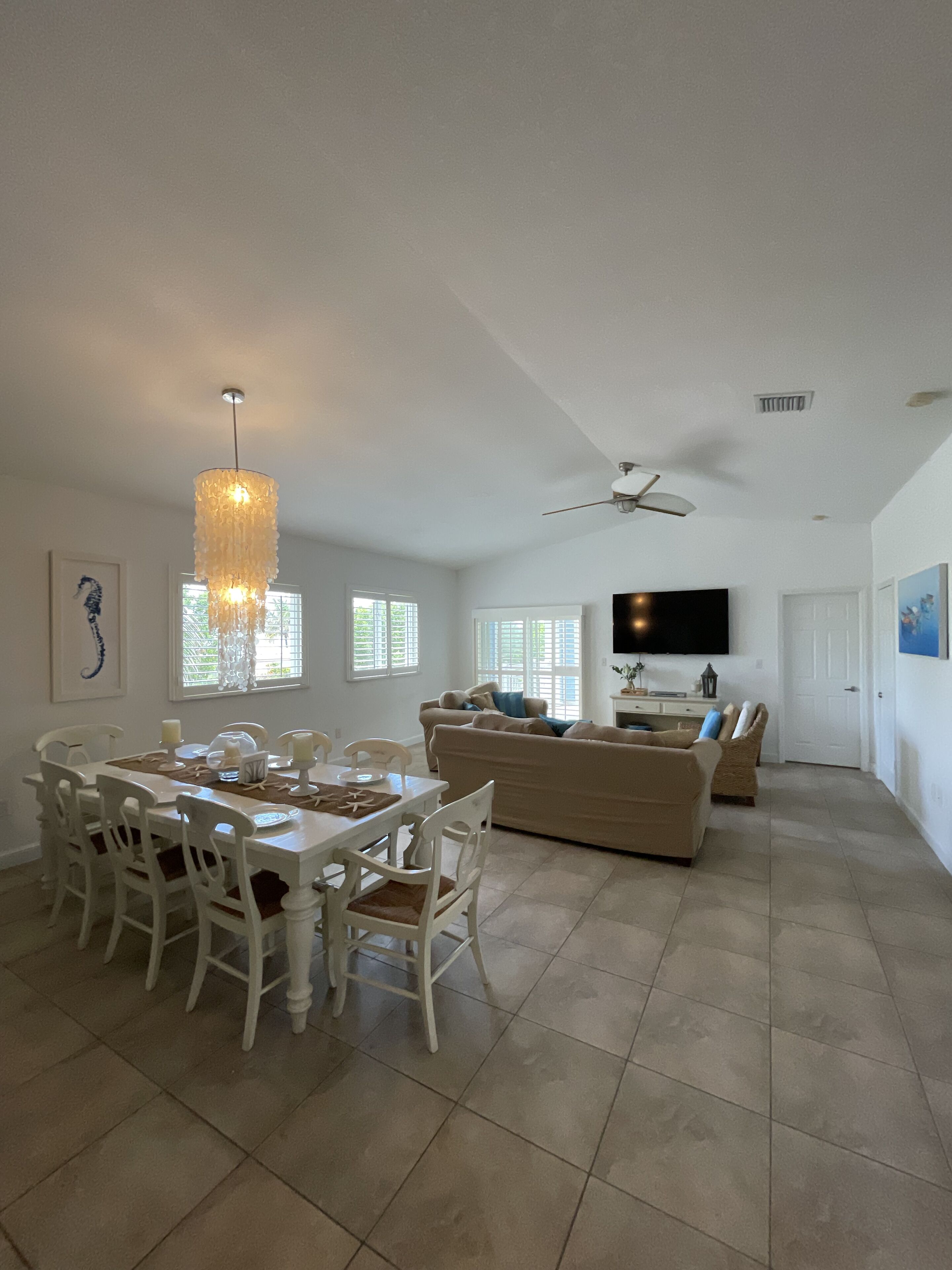 A spacious living area with a dining table, chairs, a sofa, and a television.