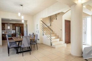 Un vaste espace de vie comprenant une salle à manger avec table et chaises, une cuisine et un escalier.