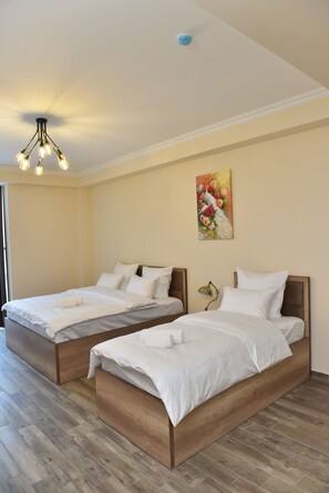 A hotel room with two wooden beds, a ceiling light fixture, and a floral painting on the wall. - Altunyan Hotel (Yerevan)