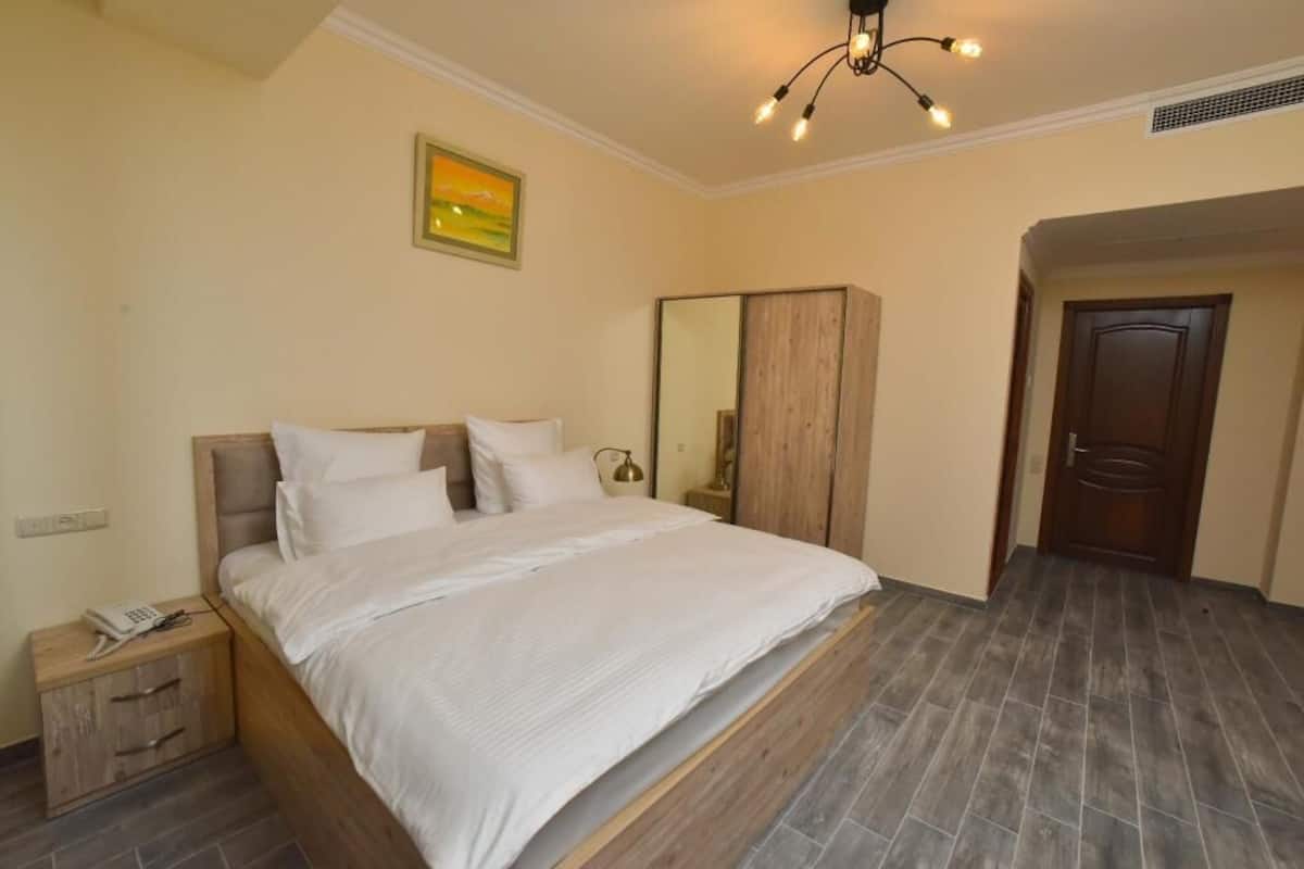 Un dormitorio con cama, mesita de noche, armario y una puerta.