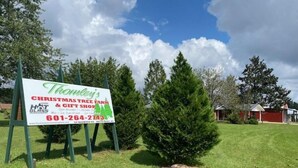 A Christmas tree farm and gift shop sign with contact information.