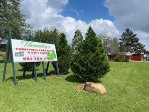 Schild eines Weihnachtsbaumhofs und Geschenkeladens mit Kontaktinformationen.