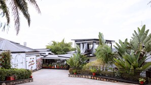 A spacious courtyard with a modern building, large potted plants, and a covered seating area.
