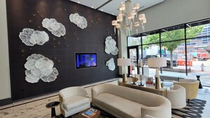 Un vestíbulo moderno con una pared oscura, motivos blancos decorativos, un televisor y zonas de estar.