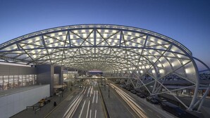 Una terminal de aeropuerto moderna con una estructura de techo en forma de arco distintiva y un largo pasillo recto.