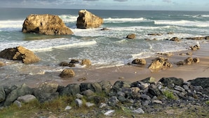 Una playa rocosa con grandes rocas y olas rompiendo contra ellas.