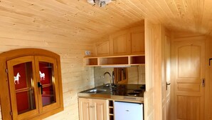 Kompakti keittiö, jossa on puiset kaapit, sisäänrakennettu pesuallas ja valkoinen jääkaappi.