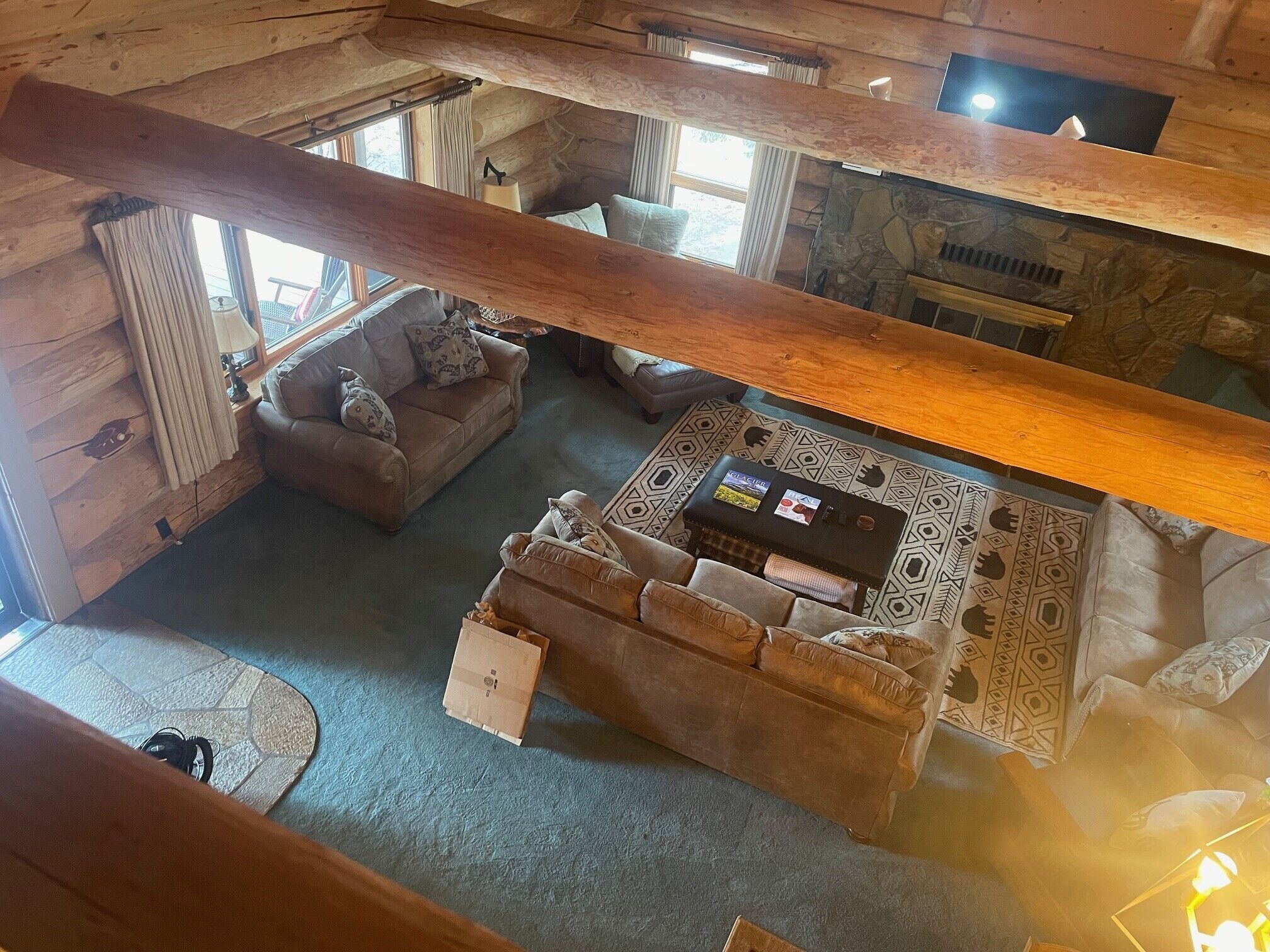 Interior acogedor de una cabaña con chimenea de piedra, techo de madera y zona de estar con sofá y una mesita de centro.
