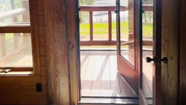 Una cabaña de madera con un amplio balcón y vistas del paisaje.