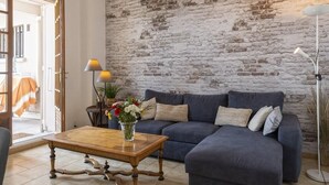 A living room with a brick wall, a dark blue sofa, a wooden coffee table, and a floor lamp. - Casa Eden Roc (Brando)