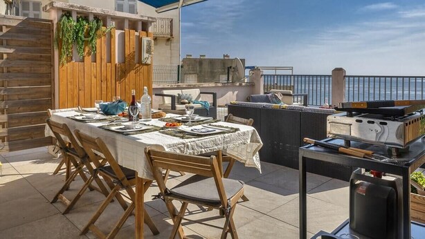 An outdoor dining area with a table set for four, a grill, and a view of the sea. - Casa Eden Roc (Brando)