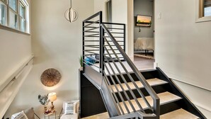 Ein modernes Interieur mit Treppe, Deckenlampe und Wand-Fernseher.