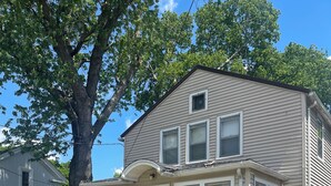 A two-story house with a front porch, a large tree, and a well-maintained lawn.