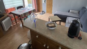 En kompakt opholdsstue med tekøkken, spiseplads og siddeområde.