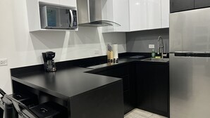 Cocina pequeña equipada con microondas, estufa y refrigerador.