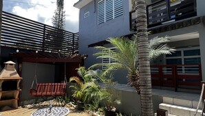 Un patio moderno al aire libre con una silla mecedora, una fuente decorativa y plantas en macetas.