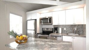 A modern kitchen with stainless steel appliances, white cabinetry, and a granite countertop. - Tropical Paradise (Islamorada)