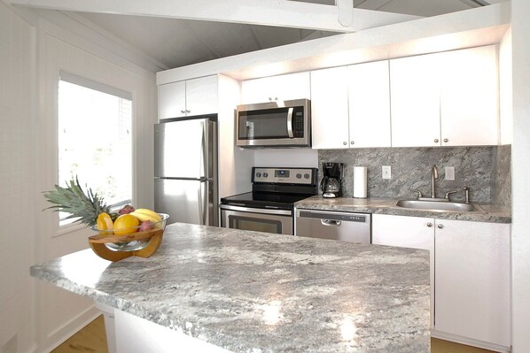 A modern kitchen with stainless steel appliances, white cabinetry, and a granite countertop.