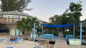 A beachside area with a wooden deck, lounge chairs, and a shaded seating area. - Tropical Paradise (Islamorada)
