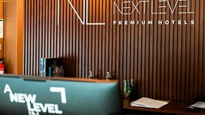 A reception desk with a sign reading "NL Next Level Premium Hotels". - Next Level Premium Hotels (Lisbon)