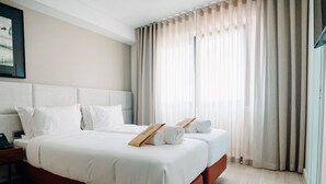 A hotel room with a large bed, two bedside tables, a bedside phone, and a window with sheer curtains. - Next Level Premium Hotels (Lisbon)