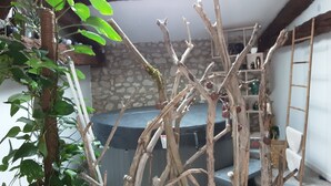 Una habitación con pared de piedra, una escalera de madera y un jacuzzi.