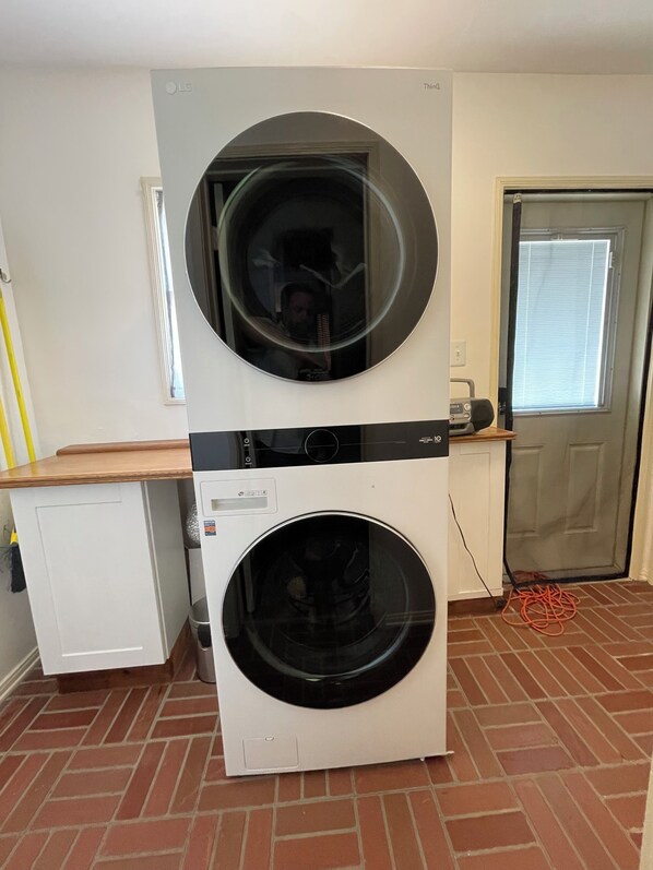 A laundry room with two stacked washing machines, a small white cabinet, and a door with a window. - Old World Charm in the Valley. Close to everything. (Los Angeles)