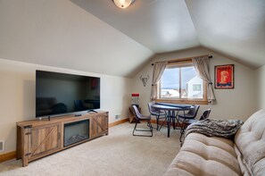 Un salon chaleureux avec un téléviseur à écran plat, un meuble de rangement en bois, une table à manger et un canapé confortable.