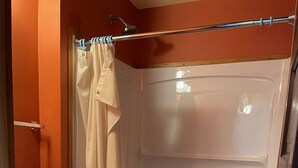 Ein Badezimmer mit Toilette, Duschkabine und Holzboden.